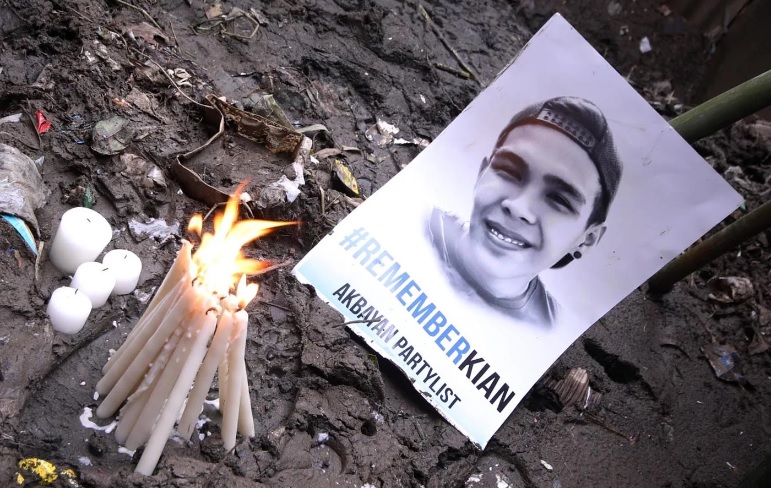 A photo of Kian delos Santos and lit candles are placed on the site where he was gunned down by cops in 2017. (Photo: Darren Langit/Rappler)