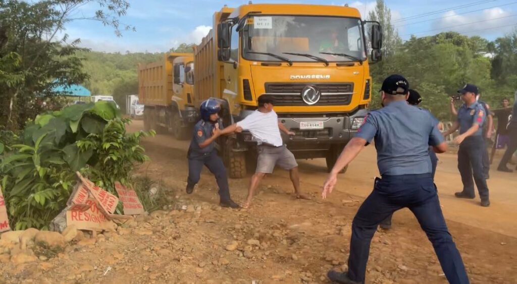 A resident of Sibuyan Island attempts to blockade mining trucks but is dispersed by the police. (Photo: Alyansa Tigil Mina via Jean Mangaluz, INQUIRER.net)