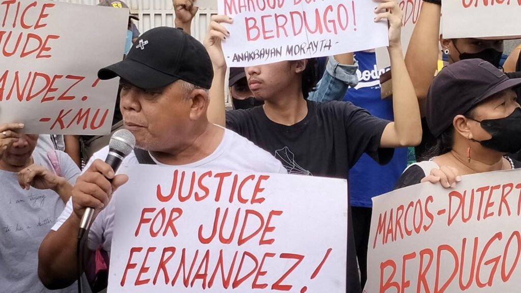 Photo of crowd protesting, with placards reading "Justice for Jude Fernandez". 