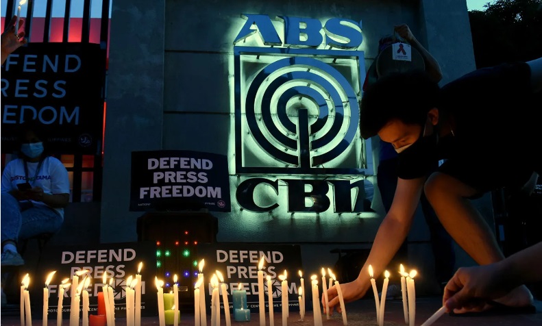 An employee of broadcasting giant ABS-CBN lights a candle during a vigil outside the network's offices in 2020. (Photo: Angie de Silva/Rappler)