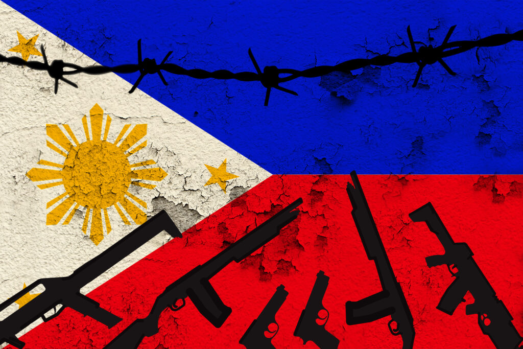 Stock photo of Philippine flag with silhouette of rifles and barbed wire.