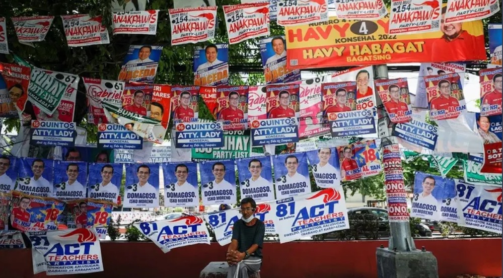 A man sits below election posters in Manila. (Photo: Reuters)